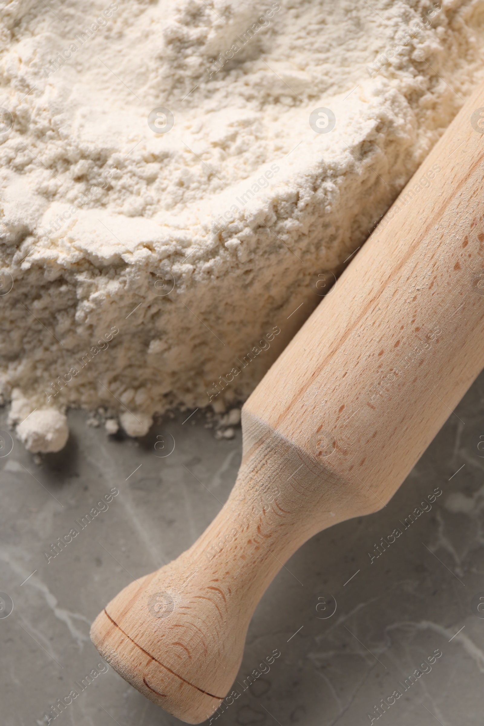 Photo of Pile of flour and rolling pin on grey marble table, top view