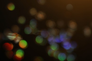 Blurred view of shiny glitter on black background. Bokeh effect