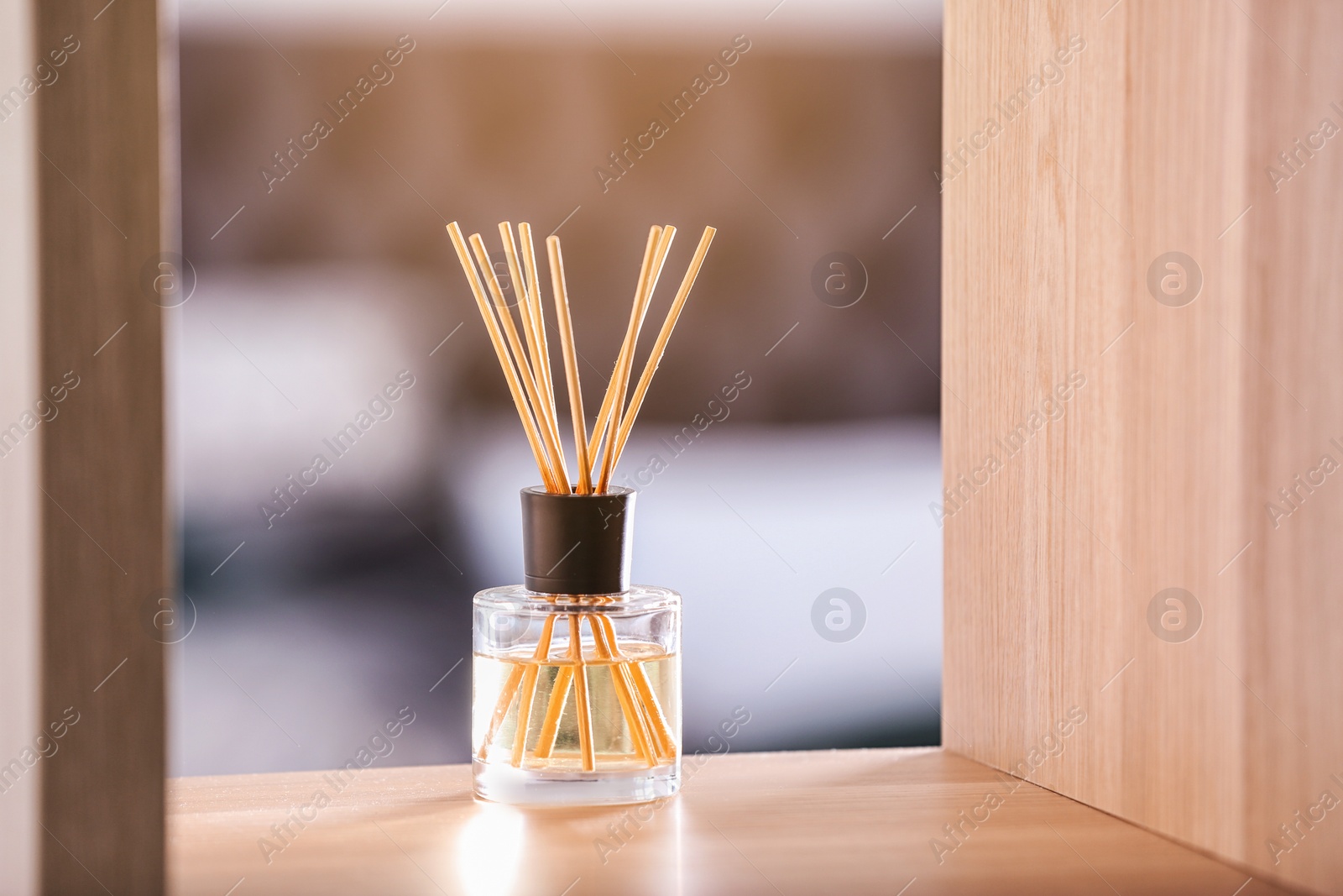 Photo of Aromatic reed air freshener on table against blurred background