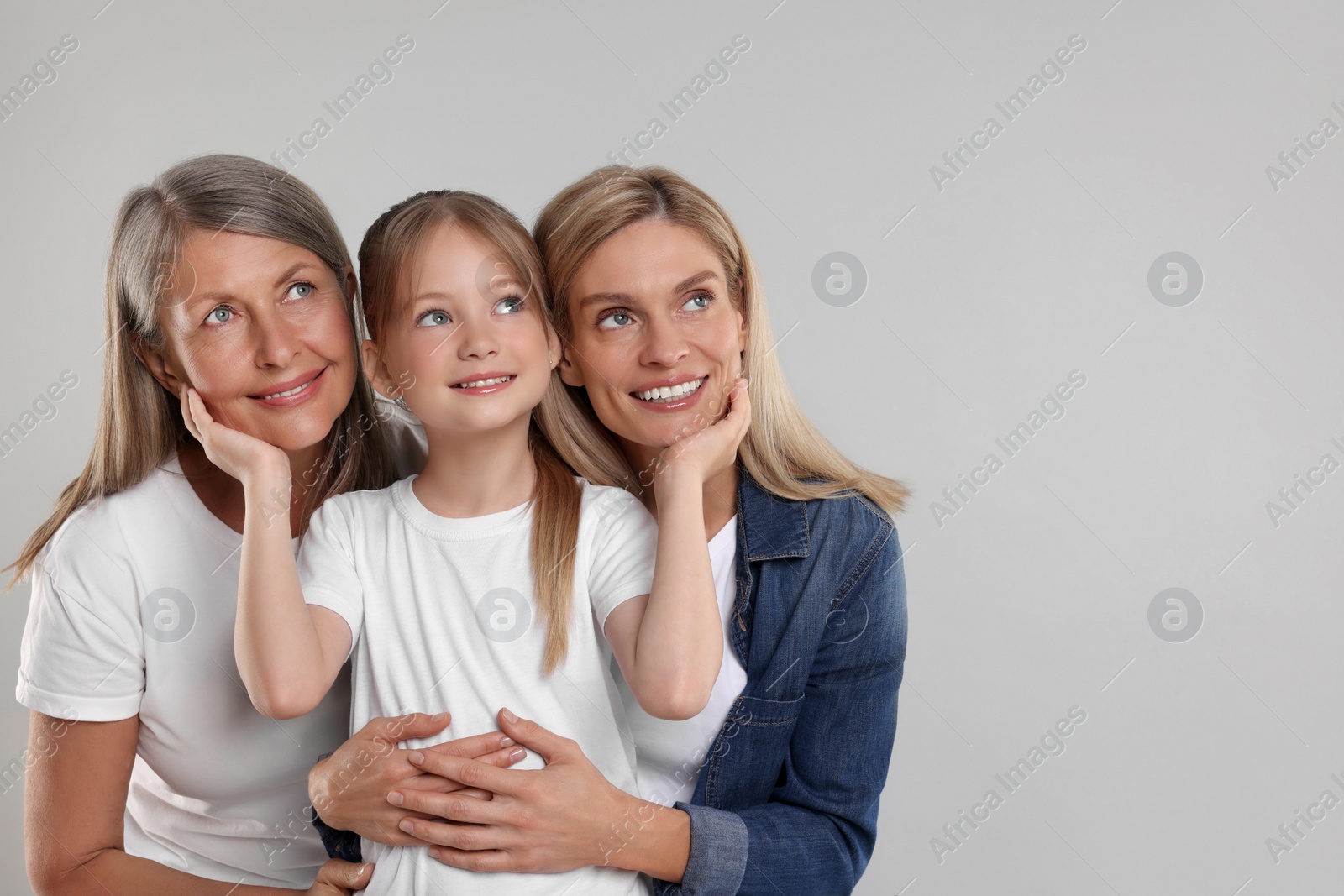 Photo of Three generations. Happy grandmother, her daughter and granddaughter on light gray background, space for text