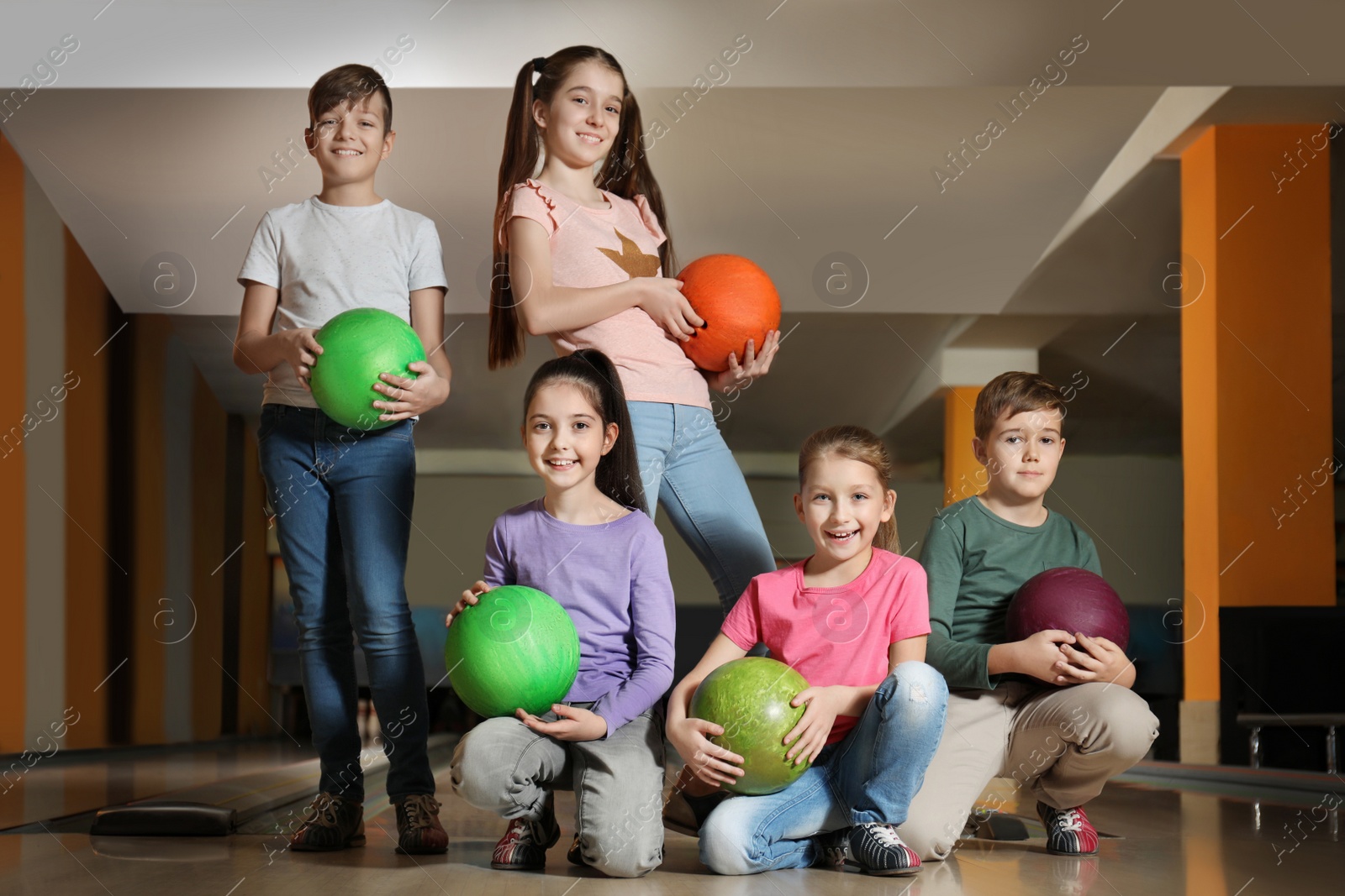 Photo of Happy children with balls in bowling club