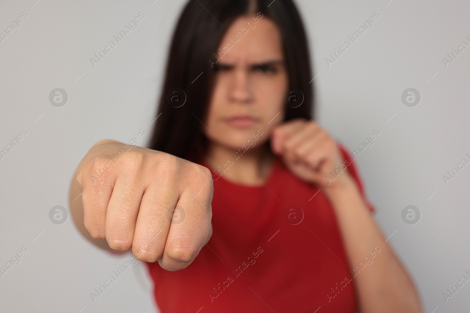 Photo of Young woman ready to fight against light grey background, focus on hand. Space for text