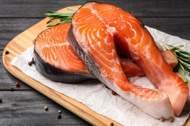 Photo of Fresh salmon steaks with spices on black wooden table