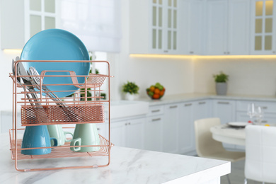 Clean dishes on drying rack in modern kitchen interior, space for text