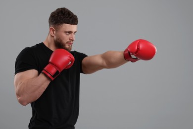 Man in boxing gloves fighting on grey background