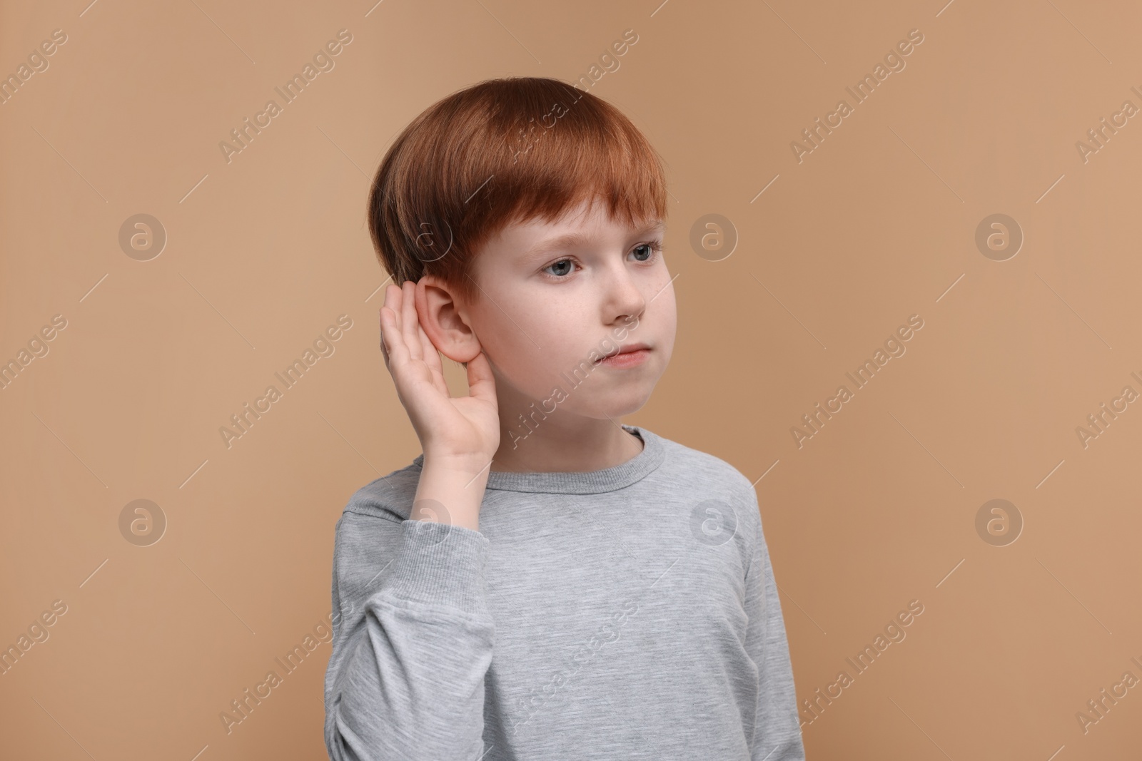 Photo of Little boy with hearing problem on pale brown background