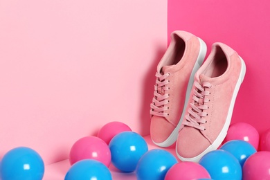 Comfortable sneakers and plastic balls on color background, space for text