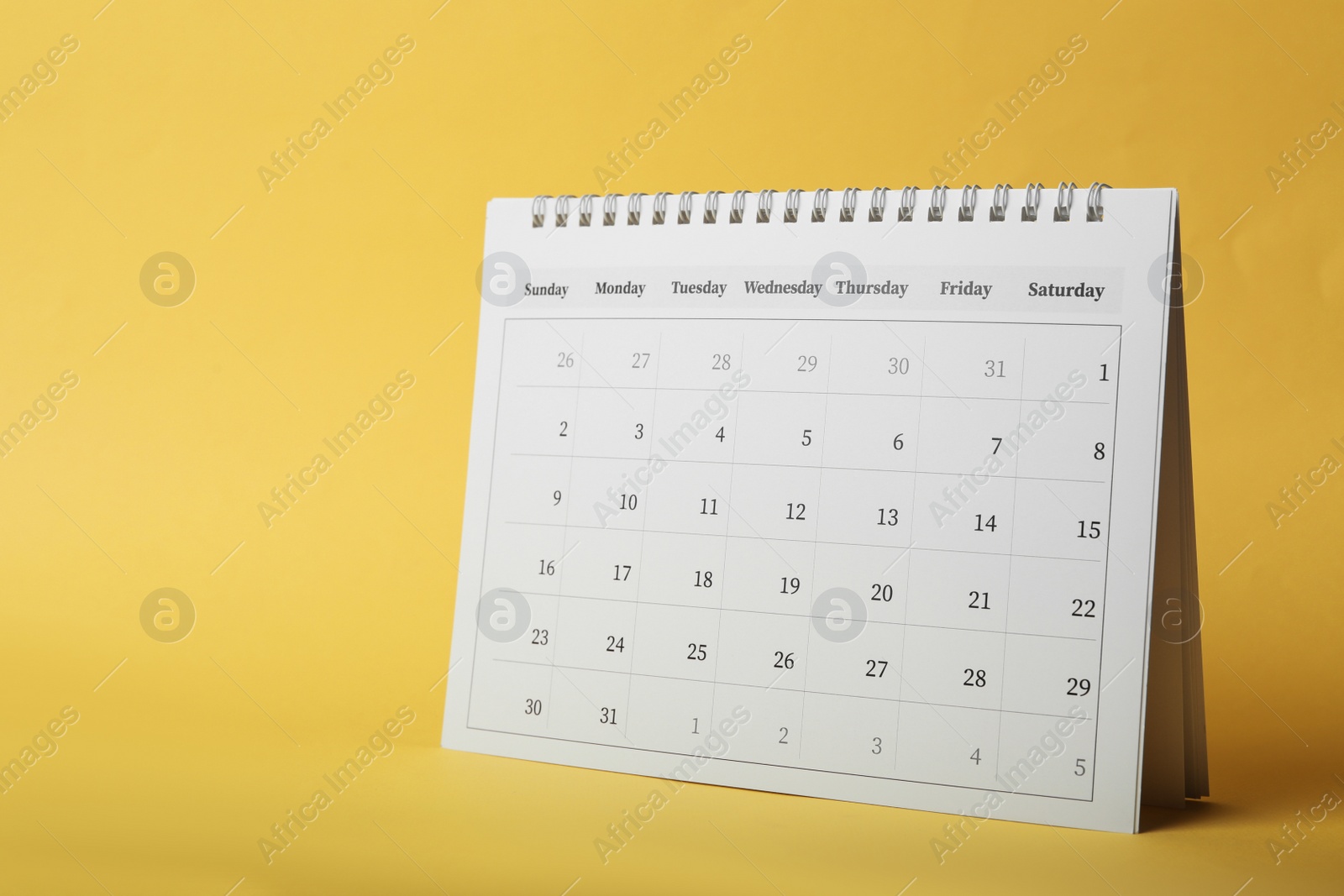 Photo of Paper calendar on yellow background. Planning concept