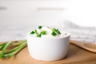 Photo of Fresh sour cream with onion on wooden board, closeup