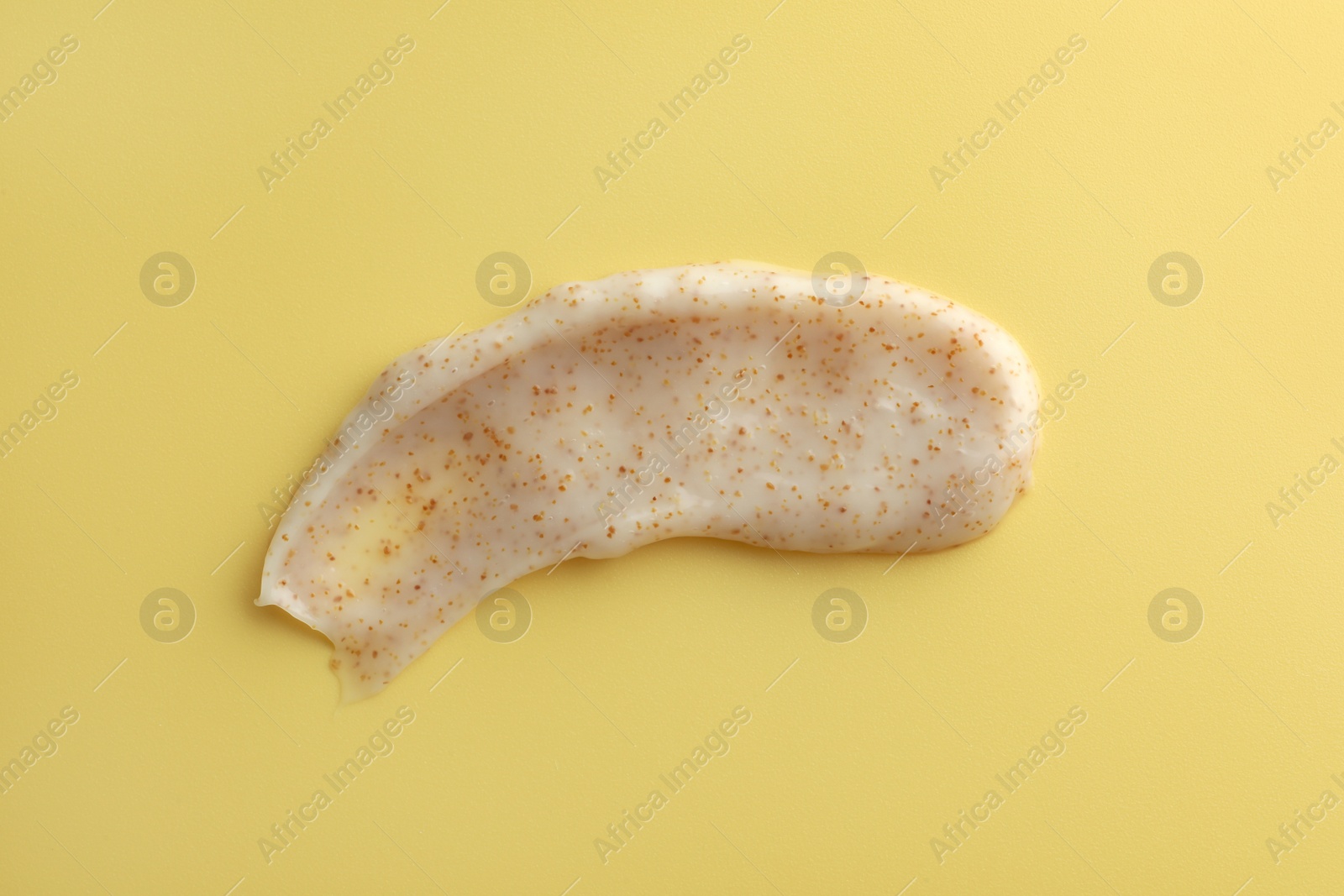 Photo of Sample of face scrub on yellow background, top view