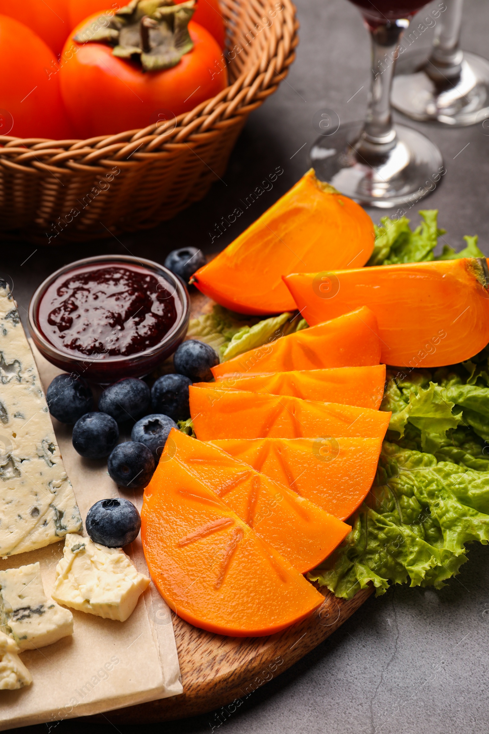 Photo of Delicious persimmon, blue cheese, blueberries and jam served on light grey table