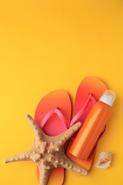 Sunscreen, starfish, shell and flip flops on orange background, flat lay with space for text. Sun protection