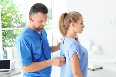 Photo of Male medical assistant examining female patient in clinic