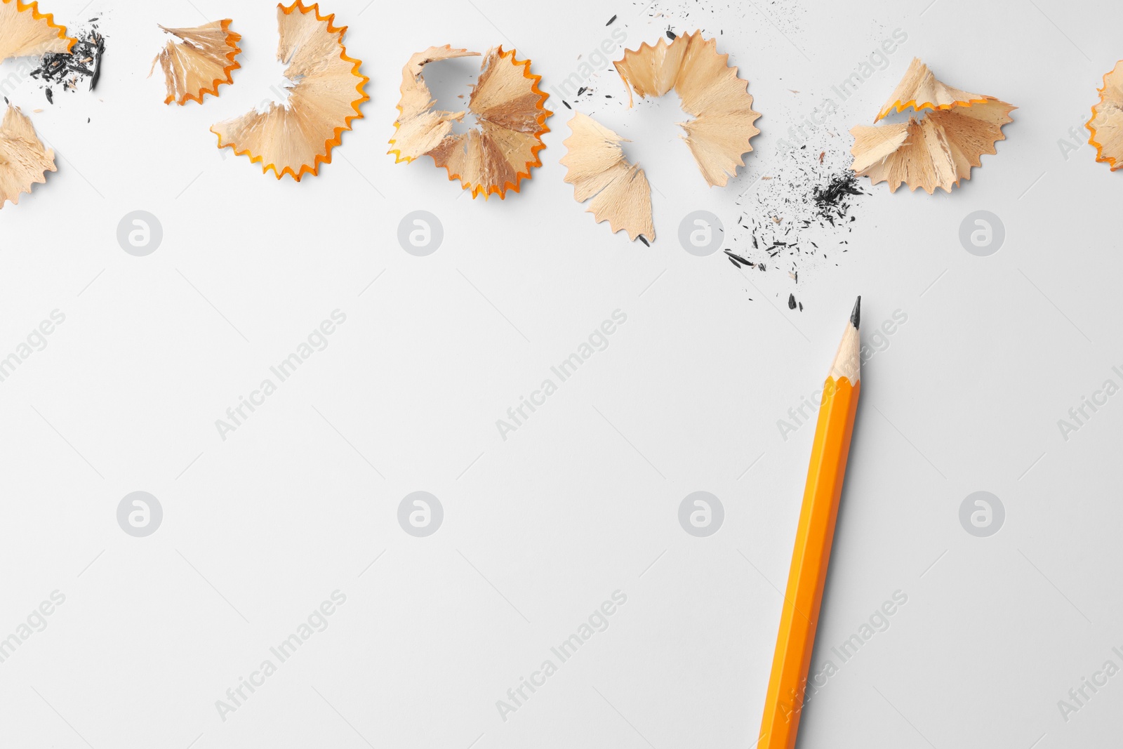 Photo of Graphite pencil and shavings on white background, flat lay. Space for text