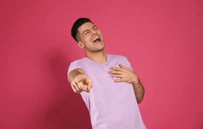 Photo of Handsome man laughing on pink background. Funny joke