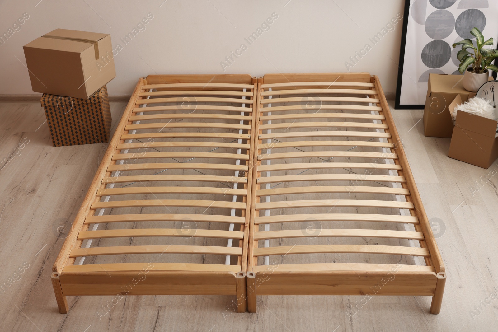 Photo of Wooden bed frame and cardboard boxes on floor in room