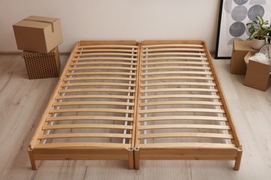 Photo of Wooden bed frame and cardboard boxes on floor in room