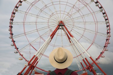 Photo of Teenage boy near large Ferris wheel outdoors