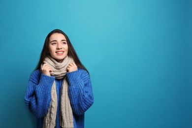 Photo of Young woman wearing warm clothes on color background, space for text. Winter season