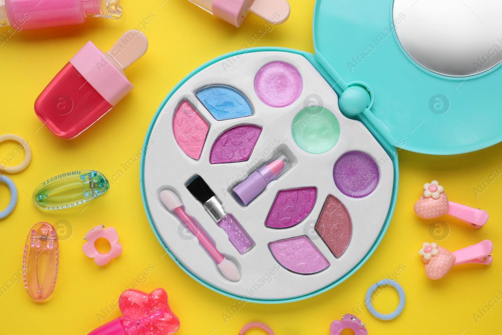 Photo of Decorative cosmetics for kids. Eye shadow palette, lipsticks and accessories on yellow background, flat lay