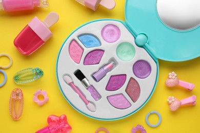 Photo of Decorative cosmetics for kids. Eye shadow palette, lipsticks and accessories on yellow background, flat lay