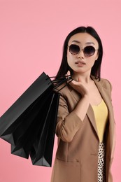 Beautiful woman with shopping bags on pink background