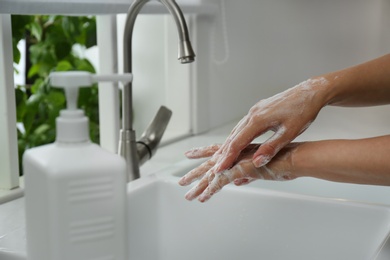 Photo of Woman washing hands with antibacterial soap indoors, closeup. Personal hygiene during COVID-19 pandemic