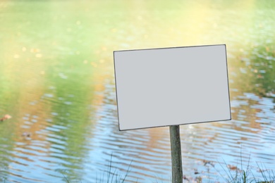 Empty sign board near pond. Space for text