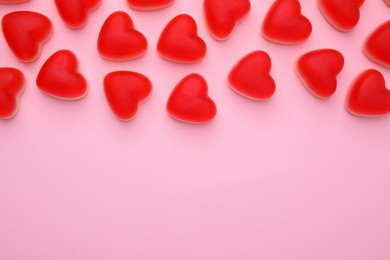 Delicious heart shaped jelly candies on pink background, flat lay. Space for text