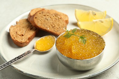 Fresh pike caviar in bowl, lemon and bread on light table, closeup