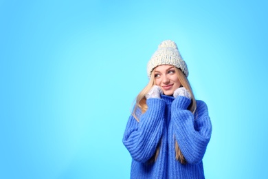 Photo of Portrait of emotional young woman in stylish hat, sweater and mittens on color background, space for text. Winter atmosphere