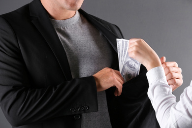 Photo of Woman giving bribe money to man on dark background, closeup