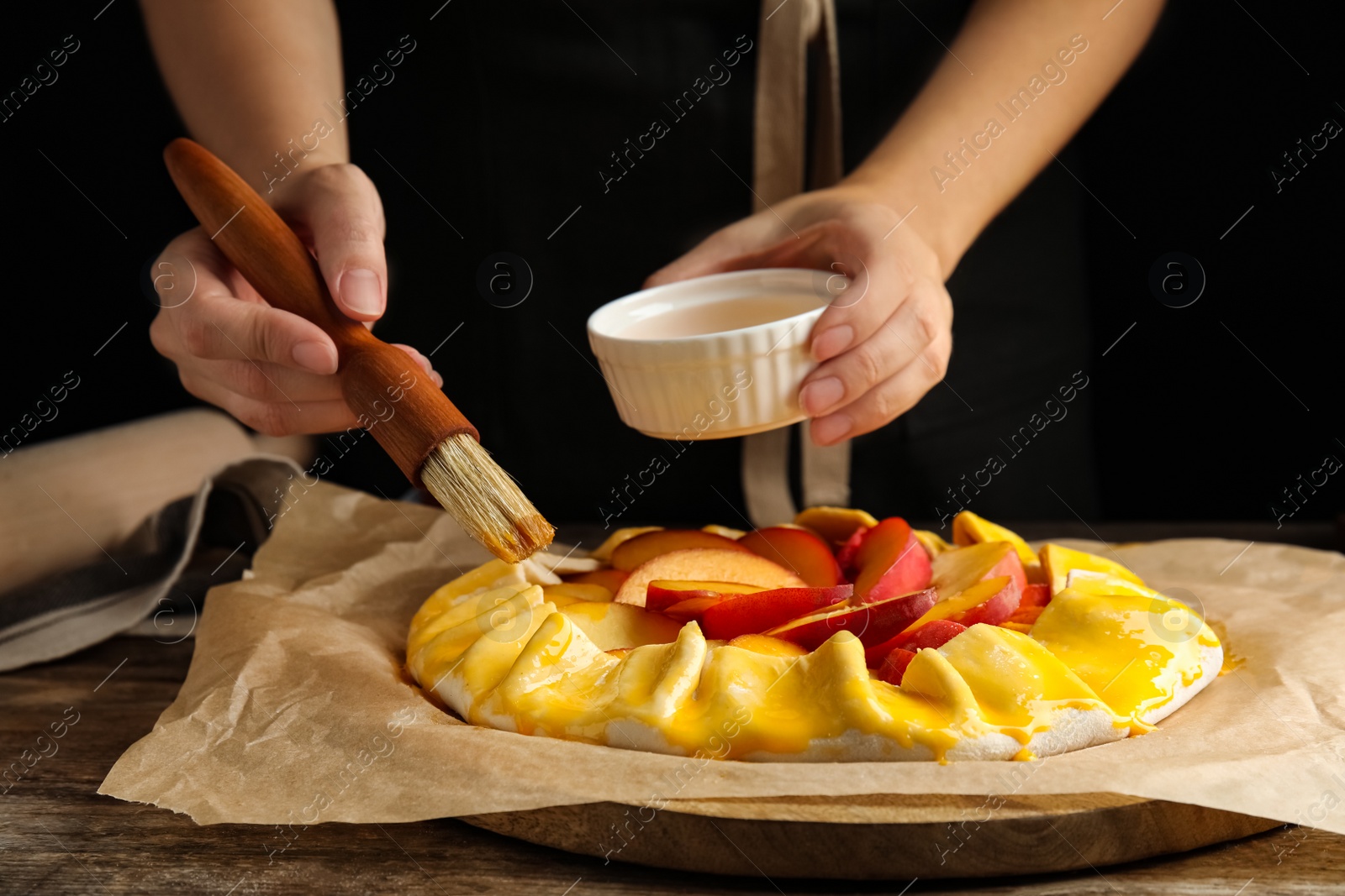 Photo of Woman making peach pie at wooden table, closeup