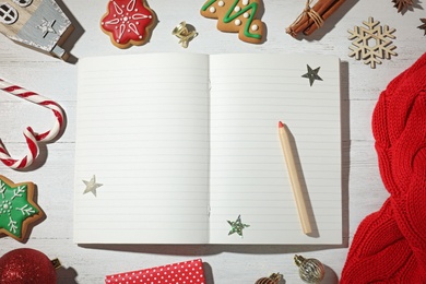 Flat lay composition with empty notebook and Christmas decorations on white wooden table, space for text. Writing letter to Santa Claus