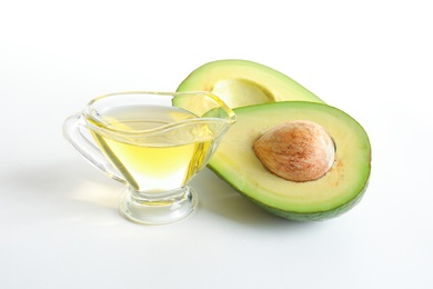 Photo of Gravy boat with oil and ripe fresh avocado on white background