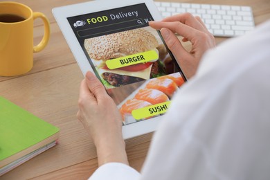 Photo of Woman using tablet for ordering food online at table indoors, closeup. Concept of delivery service