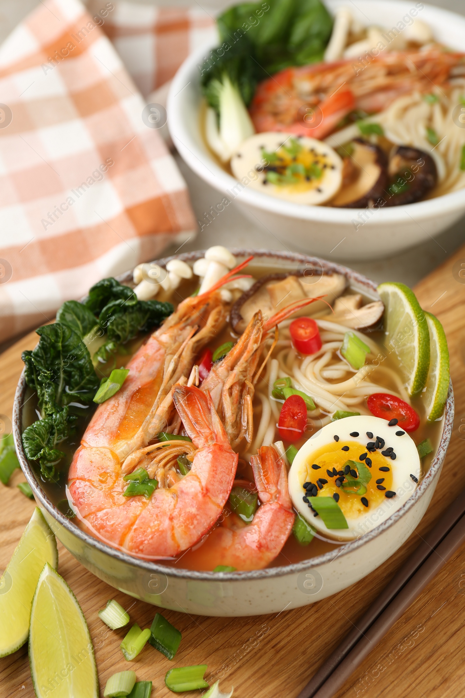 Photo of Delicious ramen with shrimps and egg in bowl served on table, closeup. Noodle soup