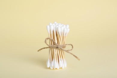 Bunch of wooden cotton buds on beige background