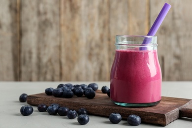 Jar with healthy detox smoothie and blueberries on table