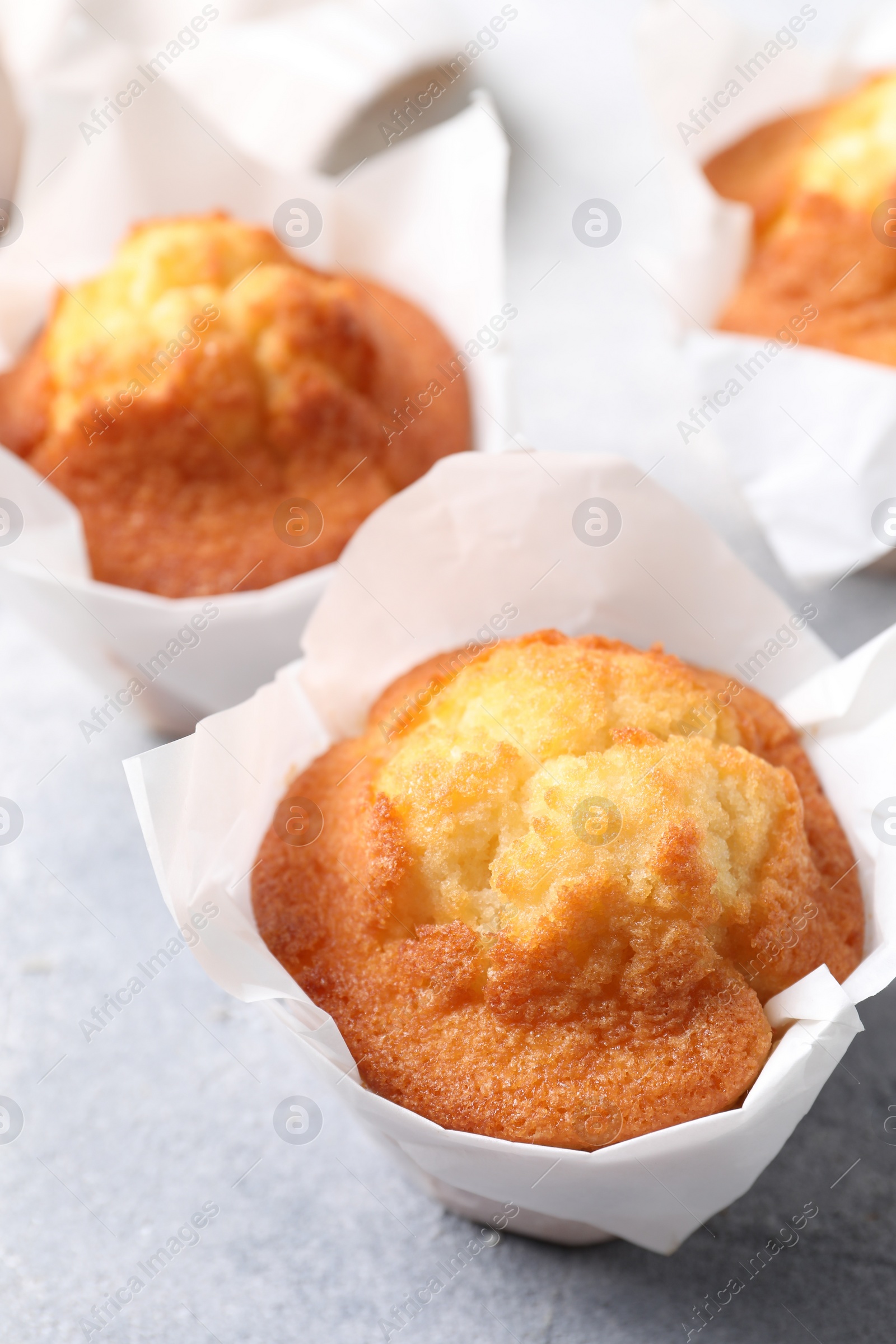 Photo of Delicious sweet muffins on light grey textured table, closeup