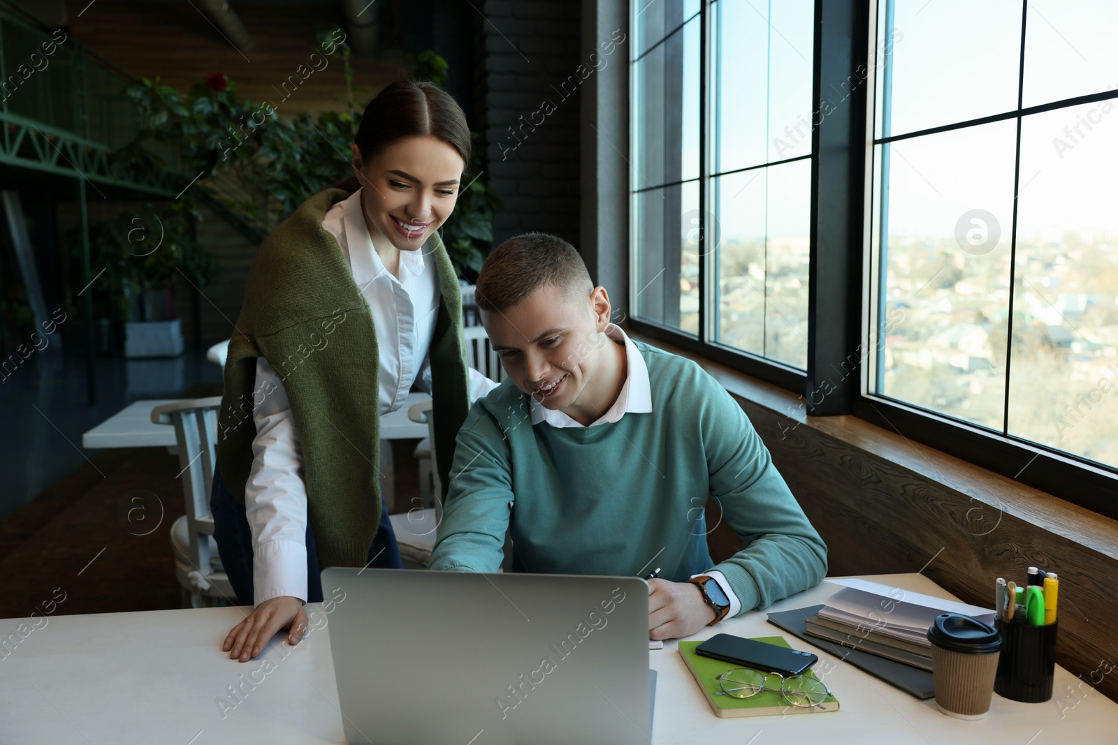 Photo of Young students with laptop studying at table in cafe