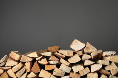 Photo of Cut firewood on grey background. Space for text