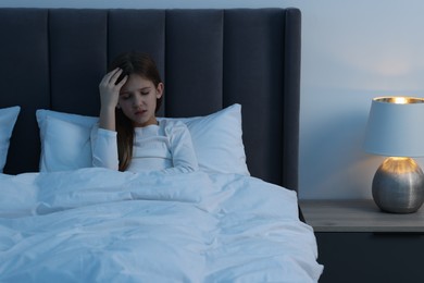 Little girl suffering from headache in bed at night