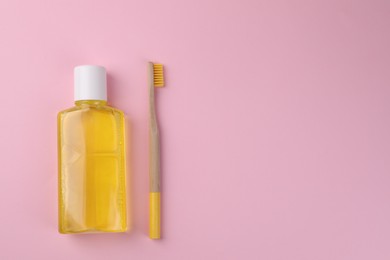 Photo of Fresh mouthwash in bottle and toothbrush on pink background, top view. Space for text