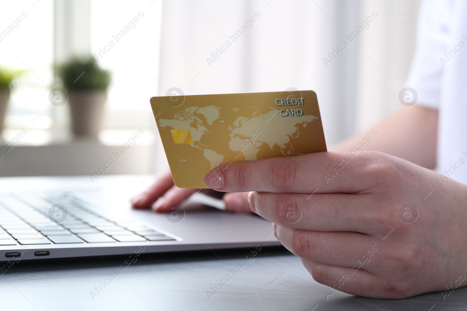 Photo of Online payment. Woman with laptop and credit card at white table, closeup