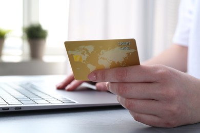 Photo of Online payment. Woman with laptop and credit card at white table, closeup