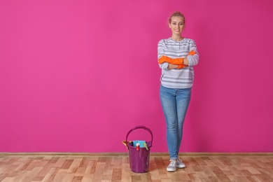 Woman with cleaning supplies near color wall