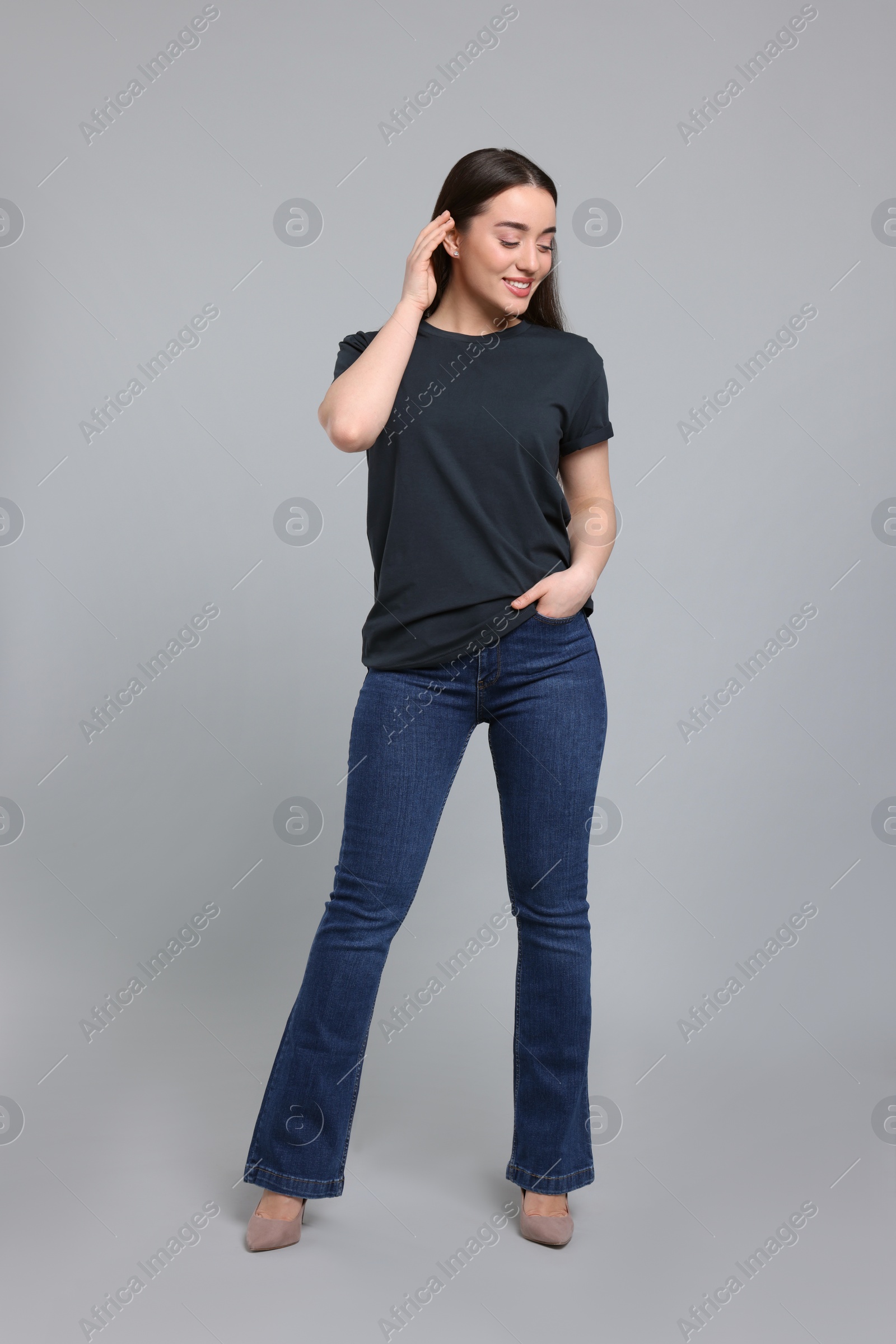 Photo of Young woman in stylish jeans on grey background