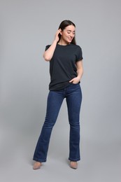 Young woman in stylish jeans on grey background