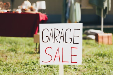 Photo of Sign Garage sale written on cardboard in yard, closeup